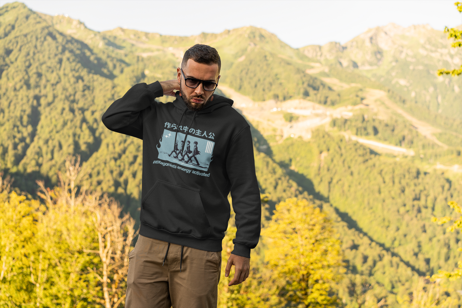 Man wearing a black hoodie with a graphic design in a mountainous landscape