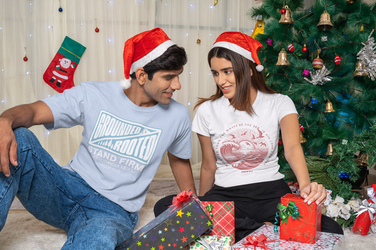 Young-couple-opening-gifts-near-christmas-tree-wearing-tees