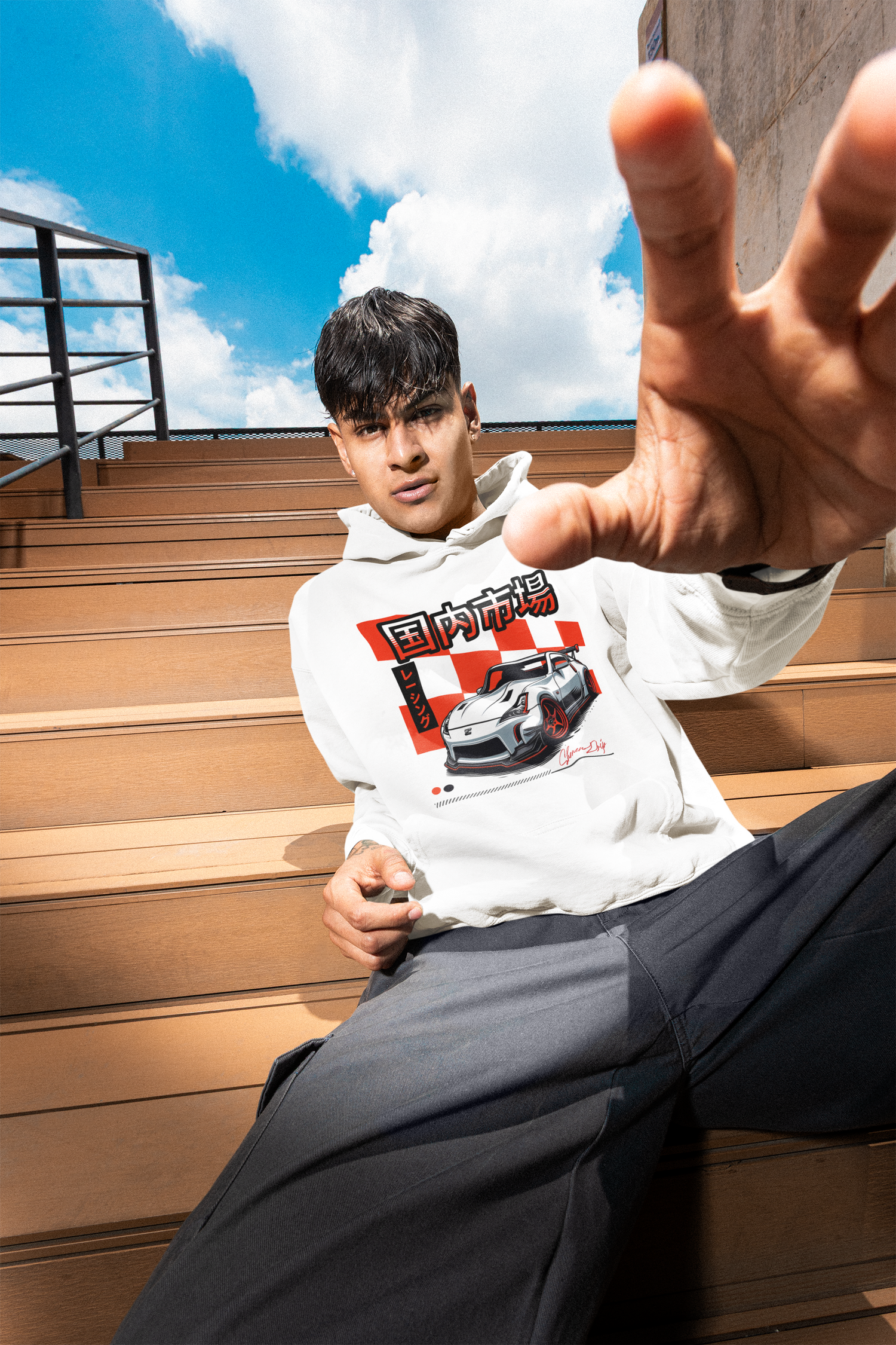 Person wearing a hoodie with a car graphic on a wooden staircase