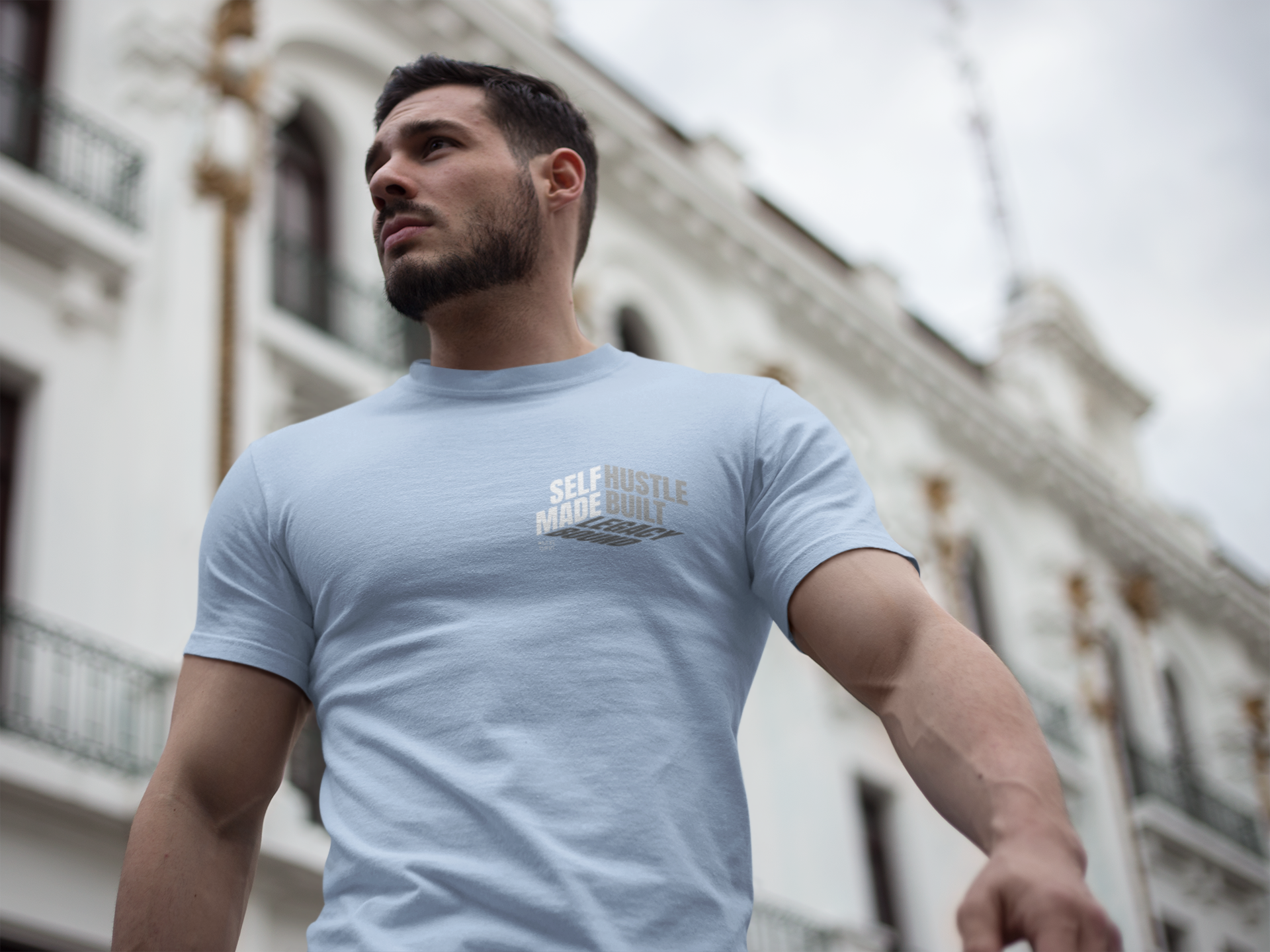 person-wearing-t-shirt-front-of-tee-that-says-self-made-hustle-built-legacy-bound-color-blue