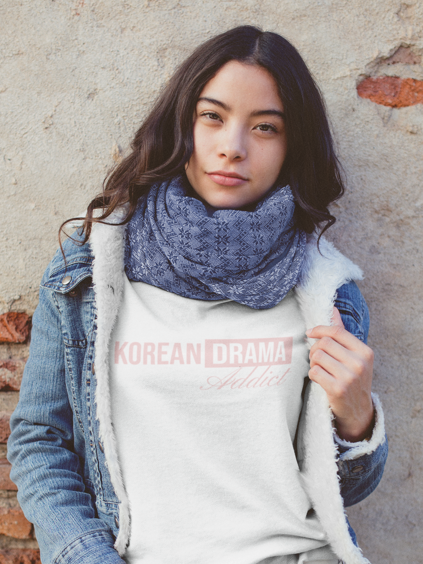 Person wearing a hoodie with 'Korean Drama Addict' text against a brick wall.