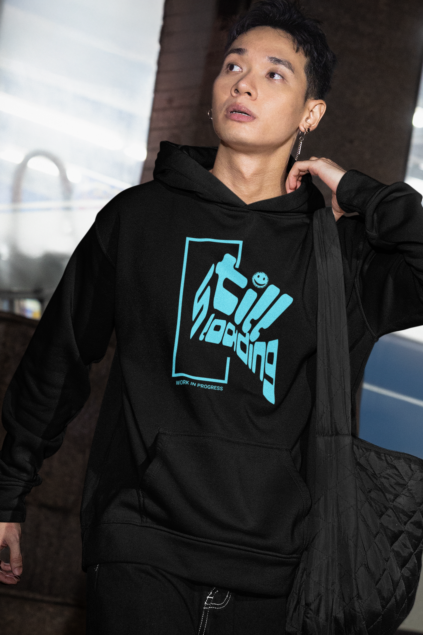 person-wearing-hoodie-with-blue-graphic-design-that-says-still-loading-work-in-progress-color-black