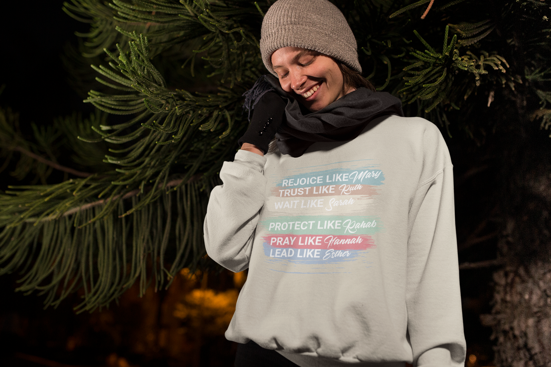 Person wearing a gray sweatshirt with motivational phrases in front of trees