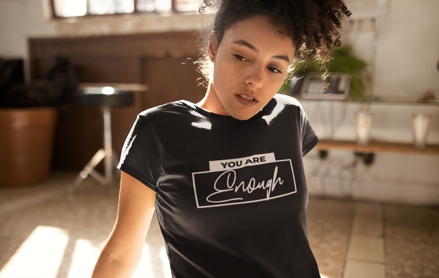 Person wearing a black t-shirt with 'YOU ARE Enough' text in a kitchen setting